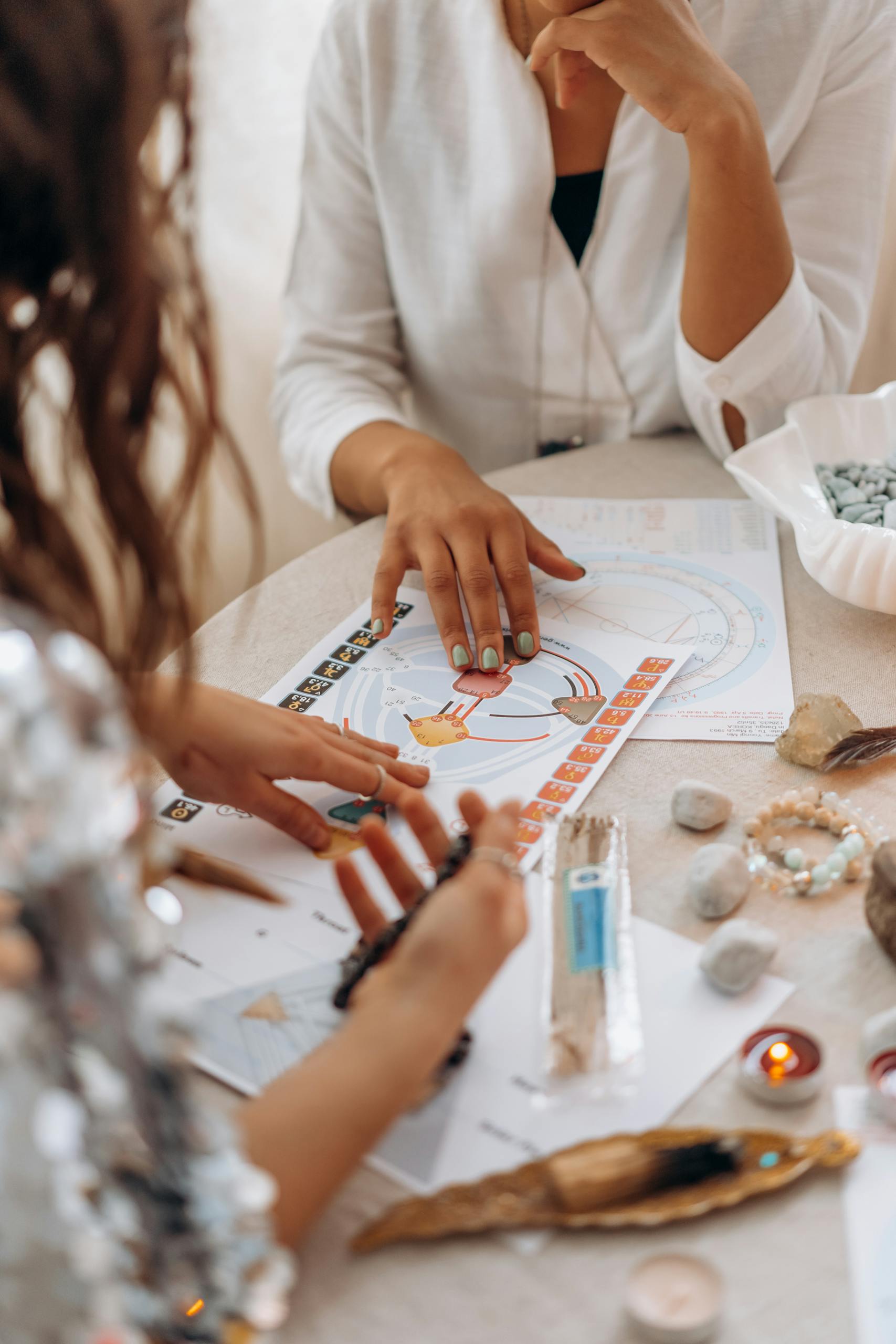 Two women exploring astrology, human design and tarot readings at a table with stones and candles.